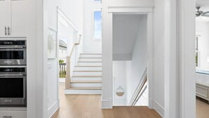 Una cocina moderna con electrodomésticos integrados, una escalera que sube a un balcón, y vistas al exterior.
