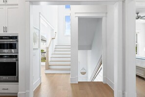 Eine moderne Küche mit Einbaugeräten, einer Treppe, die zu einem Balkon führt, und Außenblick.