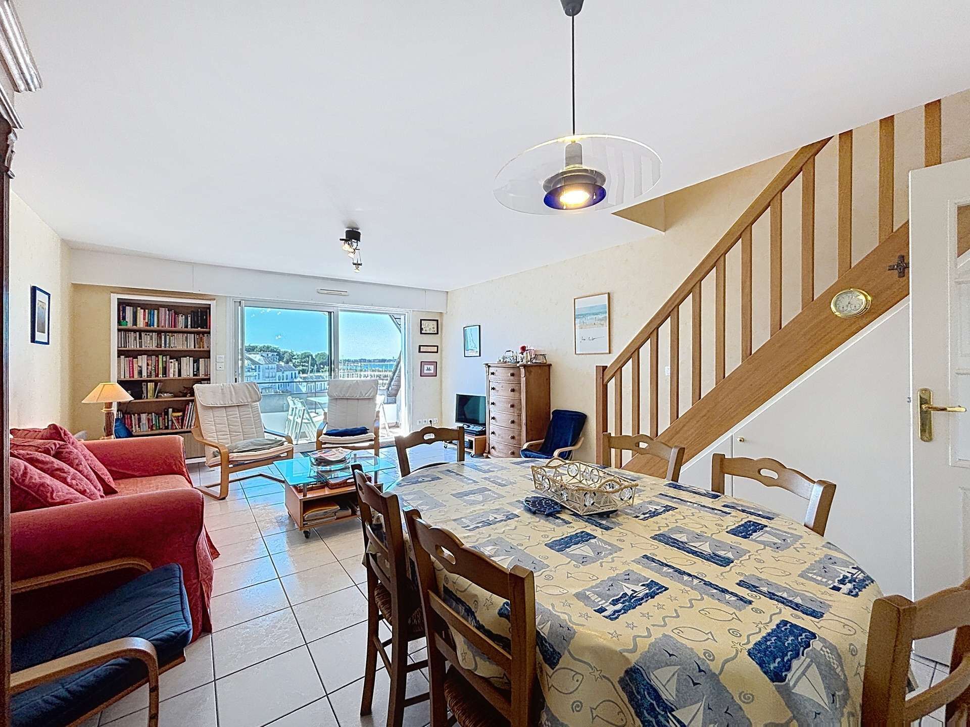 Un espace repas comprenant une table, des chaises, une bibliothèque, un canapé et un escalier.