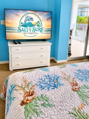 A bedroom with a TV displaying 'Sally Surf Getaways Destin Fort Walton Beach,' a white dresser, and a floral quilt. - New Listing! Summer Openings! Destin West Resort (Fort Walton Beach)