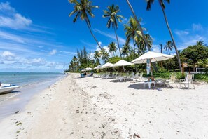 Ein Strand mit Palmen, Sonnenschirmen und Liegestühlen.
