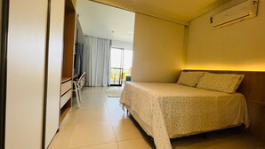 A hotel room with a bed, a desk, a chair, and a window. - Eco Resort Apartment - Carneiros Beach (Tamandaré)