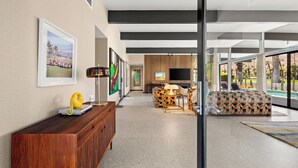 Ein modernes Wohnzimmer mit Kamin, Fernseher und Blick auf einen Pool.