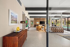 Ein modernes Wohnzimmer mit Kamin, Fernseher und Blick auf einen Pool.