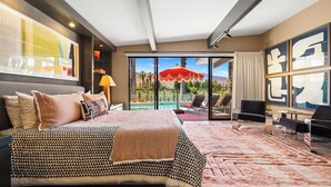 Ein Hotelzimmer mit einem großen Bett, Blick auf einen Pool und einem Essbereich.