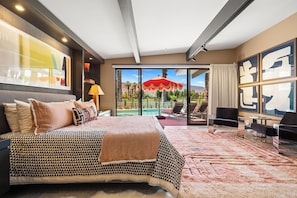Ein Hotelzimmer mit einem großen Bett, Blick auf einen Pool und einem Essbereich.