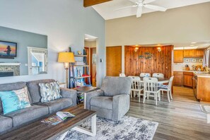 Una sala de estar con sofá, sillón, mesa de centro y una zona comedor con mesa y sillas.