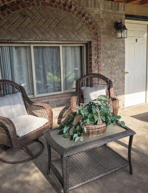A patio area with wicker furniture and a table with a plant centerpiece. - Cozy • Pet Friendly• Centrally Located (Clarksville)