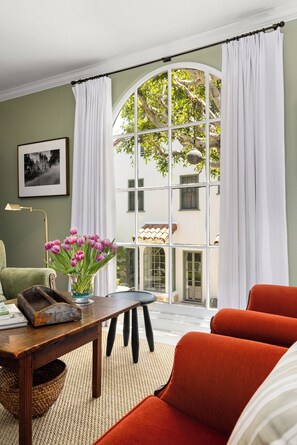 Et værelse med et stort buet vindue, et bord med blomster, en stol og en sofa.