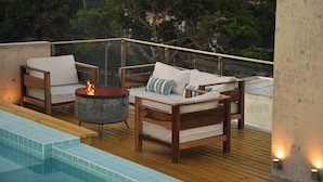 Una terraza en la azotea con piscina, cubierta de madera y un hogar para fuego.