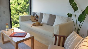 Una sala de estar acogedora con un sofá, una mesa de centro de madera y vistas a zonas verdes.