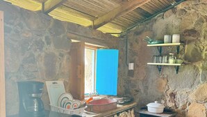 A compact kitchen with a refrigerator, stove, and a window with blue curtains. - Garden Casita | Private Bath | Carrizal (La Cruz)
