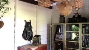 Een landelijke kamer met een houten kist, hangende lampen en een glazen kast met spullen.
