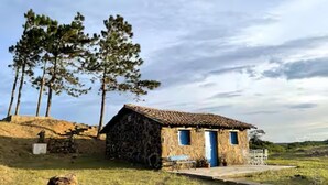 Une maison de campagne en pierre, avec un toit en tuiles, une porte bleue et un petit porche.