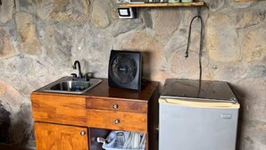 Une cuisine équipée d’un meuble en bois, d’un évier, d’un ventilateur et d’un réfrigérateur.