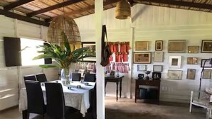 Un coin repas avec une table dressée pour quatre personnes, des chaises, un luminaire suspendu et une plante en pot.