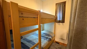 A bunk bed with a headboard, a small window with curtains, and a wall-mounted cabinet. - Comfortable studio with terrace and WIFI in Serre Chevalier (Serre Chevalier Chantemerle)