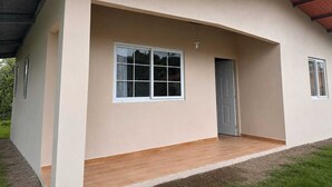 Una edificación de un nivel con techo plano, una puerta principal y un ventanal grande.