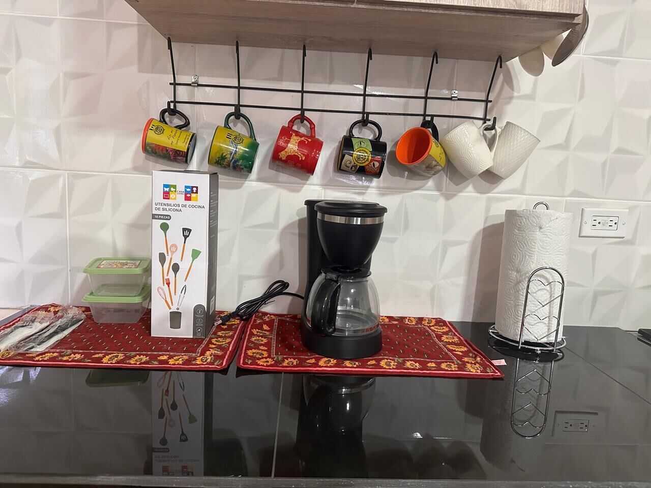 Une cuisine équipée d’une machine à café, de tasses suspendues et d’un porte-essuie-tout.