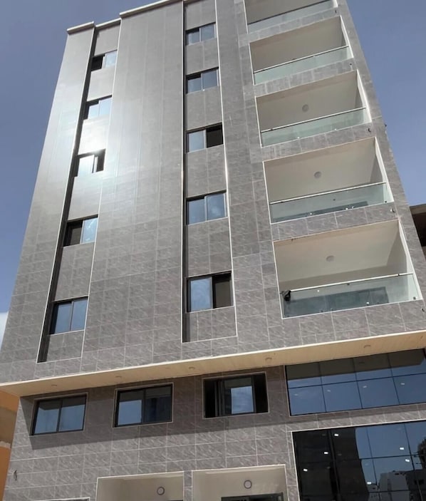 A multi-story building with a modern design, featuring a series of balconies and large windows. - Couramina (Dakar)