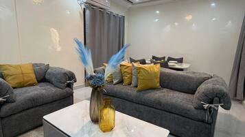 A modern living room with two grey sofas, a marble coffee table, and a vase with decorative elements.