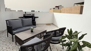 A rooftop terrace with a sofa, chairs, a table, and a potted plant. - Couramina (Dakar)