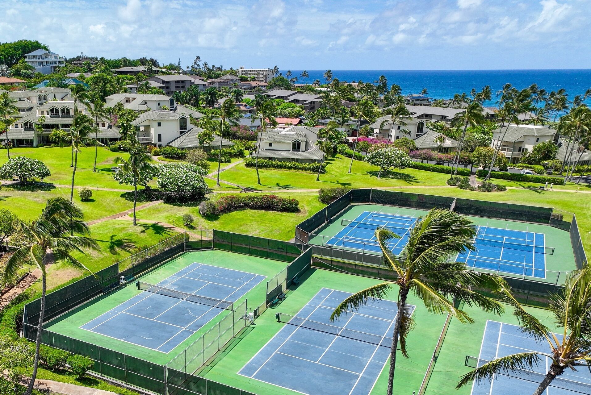 Complejo de canchas de tenis con varias pistas, rodeado de abundante vegetación y edificios residenciales.