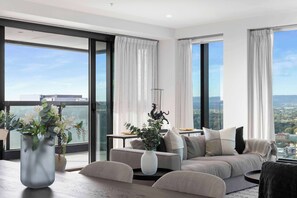 A modern living room with a sofa, a coffee table, and a vase with flowers. - Luminesque Skyhome | Executive Residence in Adelaide CBD (Adelaide)