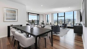 Ein modernes Wohnzimmer mit Essbereich, großen Fenstern und Blick auf die Stadt.