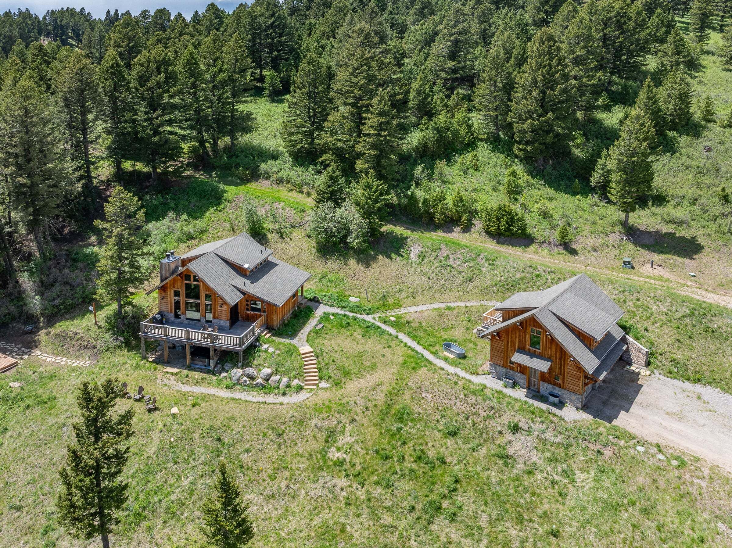 Deux cabanes en bois, chacune avec une entrée séparée, situées au cœur d’un paysage boisé.
