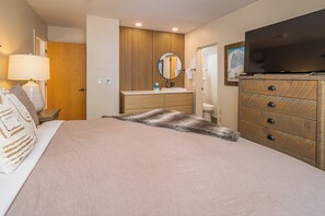Ein Hotelzimmer mit einem Bett, einem Holzschrank, einem Fernseher und einem Badezimmer.
