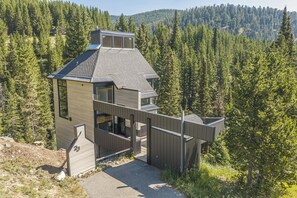 Eine moderne Holzhütte mit geneigtem Dach, großen Fenstern und einer Terrassenfläche.