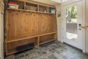 A wooden bench with hooks, a door with a peephole, and a tiled floor.