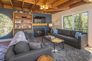 Ein gemütliches Wohnzimmer mit Kamin, großem Fenster und Bücherregal.