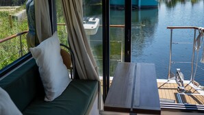 A balcony with a green sofa, a small table, and a view of boats on water.