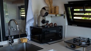 A compact kitchen with a sink, a toaster, a microwave, and a stove.