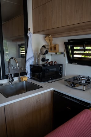 Une cuisine de taille réduite équipée d’un évier, d’un grille-pain, d’un four à micro-ondes et d’une cuisinière.
