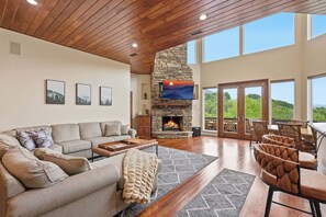 Un salón espacioso con chimenea de piedra, un sofá grande y una zona de comedor con sillas.