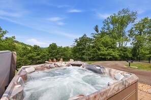 A hot tub with a marble exterior, surrounded by a lush green landscape and a clear sky.