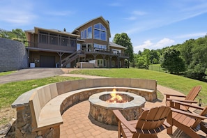 A large house with a fire pit and outdoor seating.
