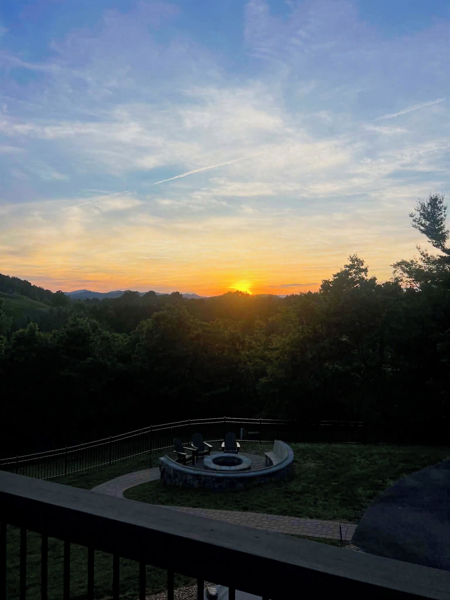 Vista al atardecer desde un balcón con una zona de estar circular y barandilla.