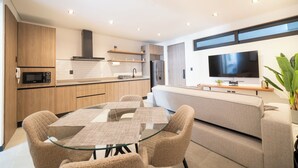 A modern kitchen with a dining area, built-in appliances, and a flat-screen TV. - Dept. Modern steps away from Quinta Av (Playa del Carmen)