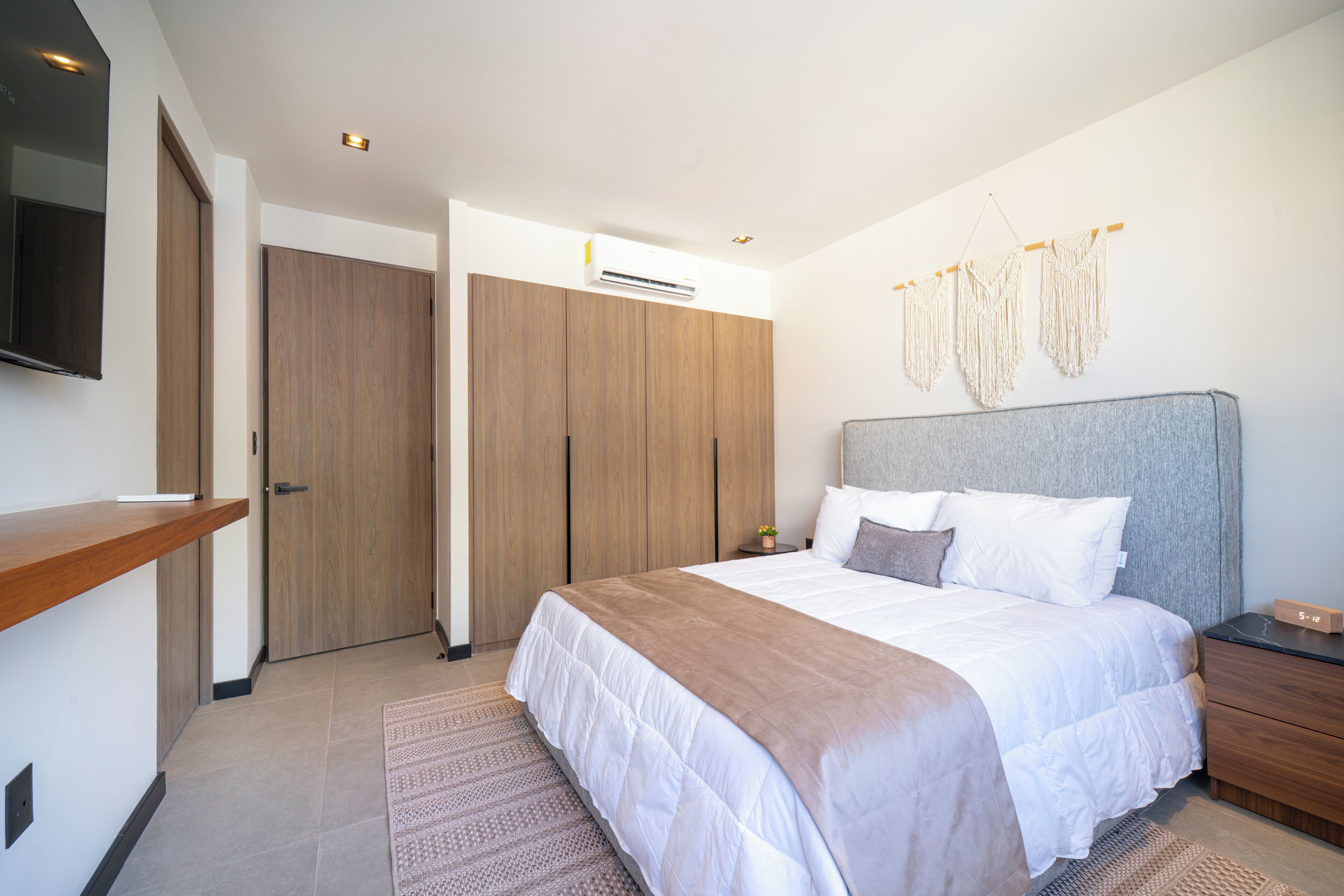 Una camera da letto con un letto, comodini, una televisione, un armadio e un condizionatore d'aria a parete.