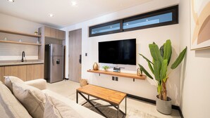 A modern kitchen with built-in appliances, a dining area with a bench, and a large potted plant. - Dept. Modern steps away from Quinta Av (Playa del Carmen)