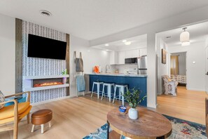Een moderne keuken met een flatscreen-tv, een open haard en barstoelen.