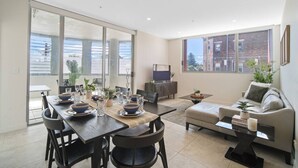 Een moderne woonkamer met een eethoek, grote ramen en een flatscreen-televisie.