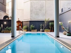 An indoor swimming pool with a wooden structure and potted plants. - Surry Hills Chic 1BR in Prime Dining & City Spots (Surry Hills)