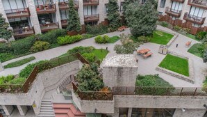 A modern building with multiple balconies, a central courtyard with greenery, and a staircase leading to an upper level. - Designer 1BR Apt | Rooftop Oasis & Fast CBD Access (Rosebery)