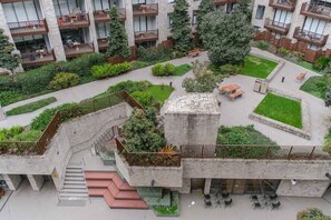 Um edifício moderno com várias varandas, um pátio central com vegetação e uma escadaria que leva a um andar superior.