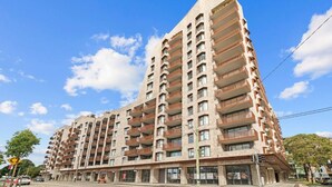 A multi-story building with a unique angular design, featuring balconies on each floor. - Designer 1BR Apt | Rooftop Oasis & Fast CBD Access (Rosebery)